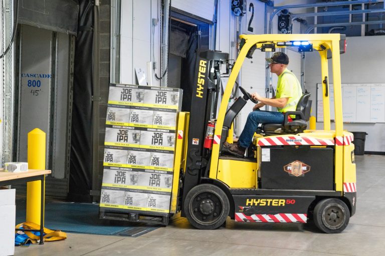 Man using a forklift to move stock into a storage unit